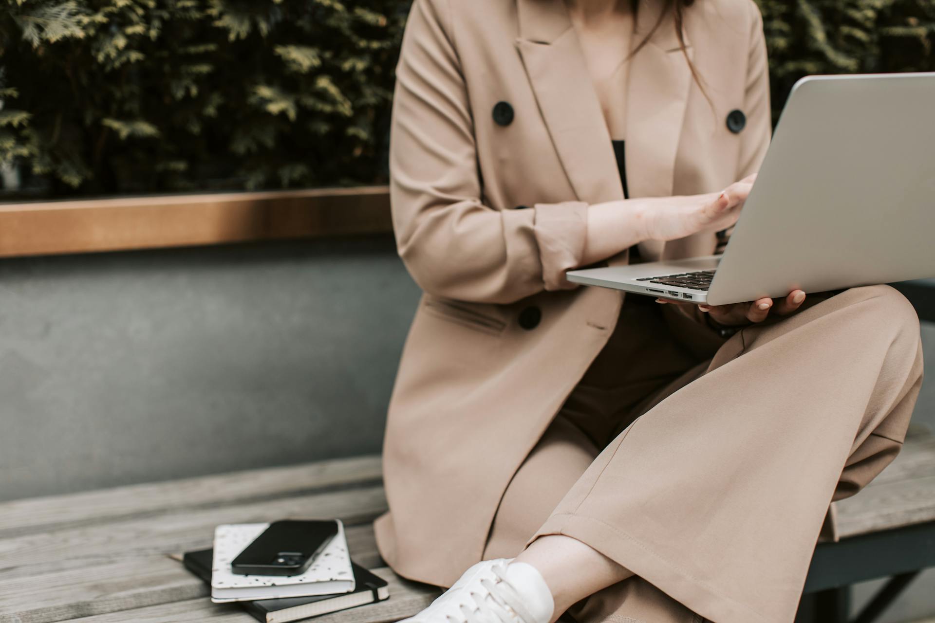 Woman sitting outdoors with a laptop and notebook, representing confidence and focus gained through financial coaching.